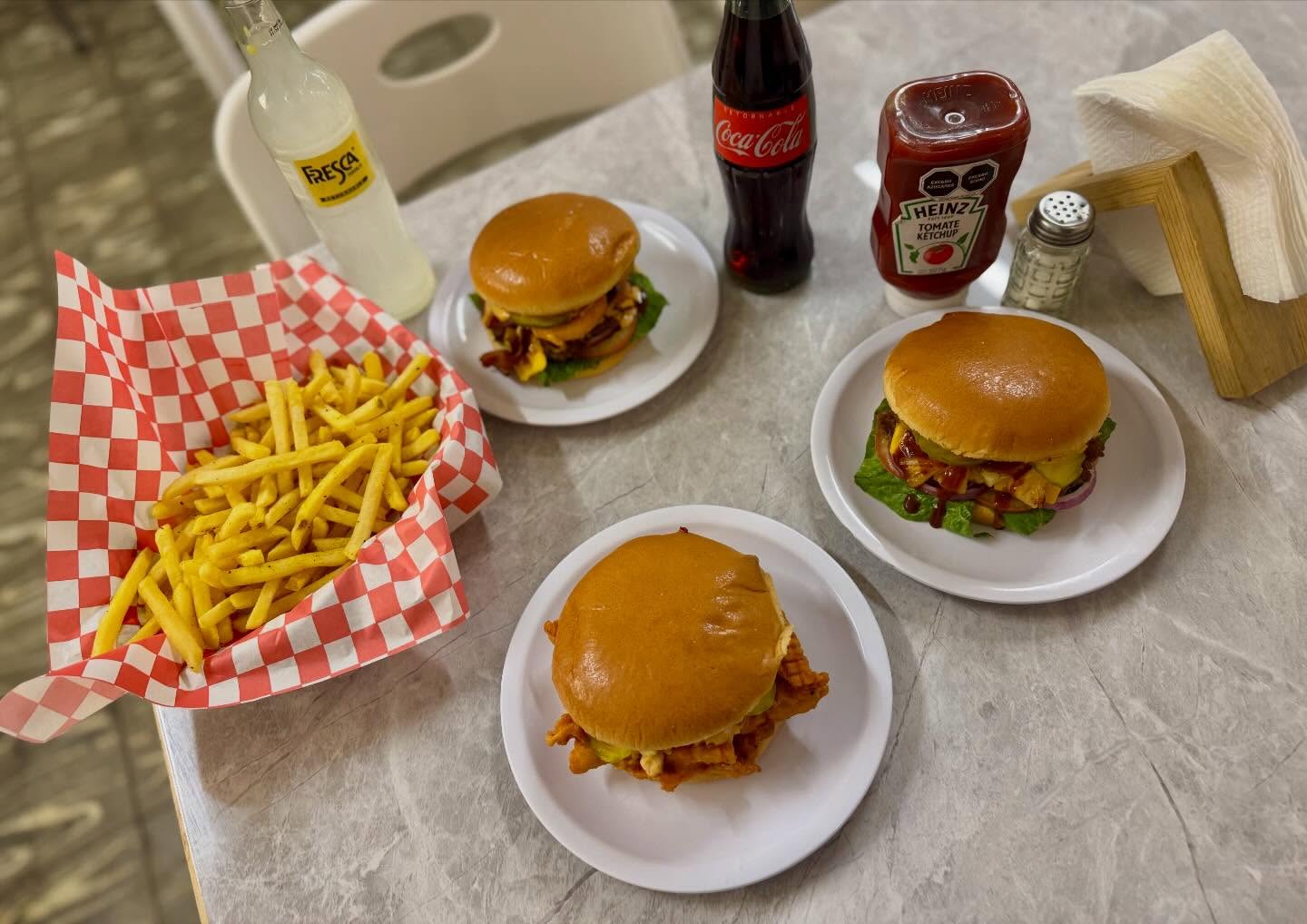Mesa con hamburguesas Only Burgers, papas fritas y refrescos